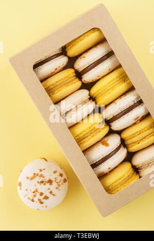 Colorful macarons in a gift box on yellow background. Flat lay. Stock Photo
