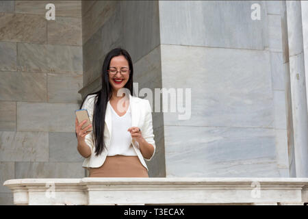 Vivacious young woman laughing at a good joke on her smart pone Stock Photo