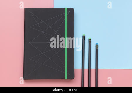Top view, notebook and pencils on pink and blue background. Stock Photo