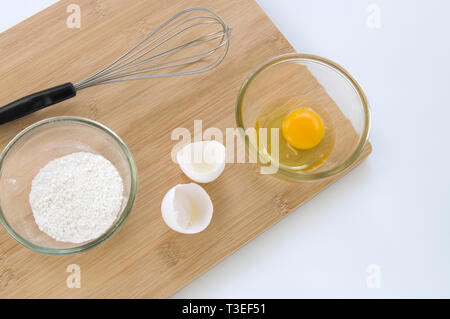 Baking Whisk and Eggs on Wooden Board Viewed from Above Stock Photo