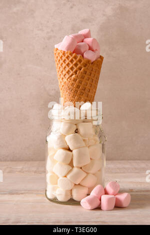A sugar Ice Cream Cone standing up in a jar of mini marshmallows and filled with pink marshmallows. Stock Photo