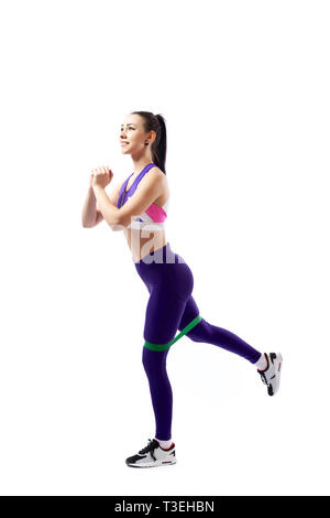 Sporty woman does  exercises on legs with sport fitness rubber bands  on white background. Photo of muscular woman in sportswear on white background.  Stock Photo