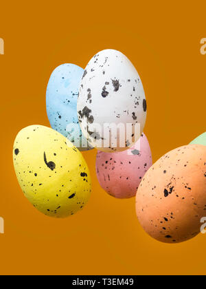 Easter scene with colored eggs flying on orange background Stock Photo