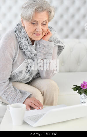 Close up portrait of senior woman using laptop while sitting on sofa Stock Photo