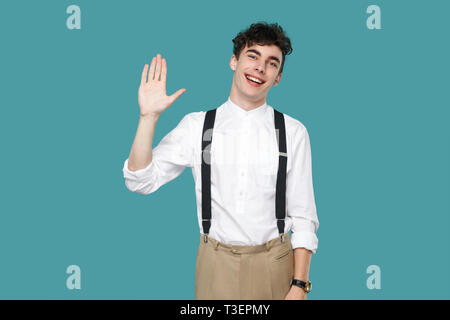 Happy excited man toothy smile and greeting. Portrait of handsome hipster curly young businessman in classic casual white shirt and suspender standing Stock Photo