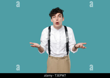 How? why? what? shocked man looking at camera and asking. Portrait of handsome hipster curly young businessman in classic casual white shirt, suspende Stock Photo