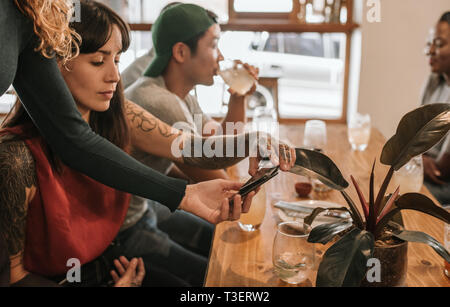Woman paying the bill with her smartphone in a bistro Stock Photo