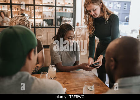 Customer paying a restaurant bill with her smartphone Stock Photo
