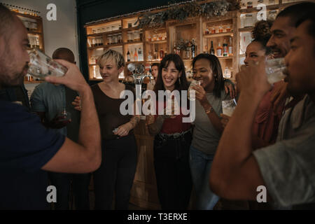 Friends drinking and talking together in a bar at night Stock Photo