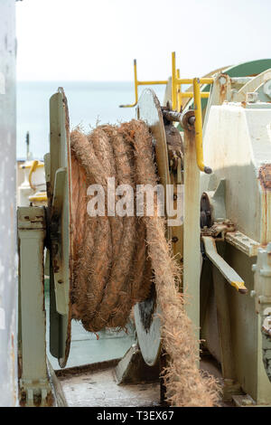 A thick rope is wrapped around a drum on deck of a ferry boat , Thailand. Close up Stock Photo