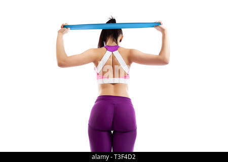 Beautiful young  womandoing exercises to strengthen the back and arms with sport fitness rubber bands  in fitness gym isolated over white background.  Stock Photo