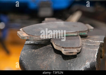 A set of two old automobile brake pads on a garage. Stock Photo