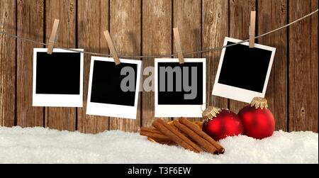 blank instant photos hanging on the clothesline in front of wooden background with snow and christmas balls - christmas background Stock Photo