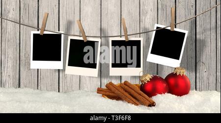 blank instant photos hanging on the clothesline in front of wooden background with snow and christmas balls - christmas background Stock Photo