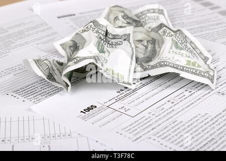 1065 tax form lies near crumpled hundred dollar bills on a Table. US Return for parentship income Stock Photo