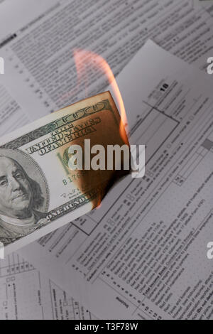 1065 tax form and a burning hundred dollar bill on a Table. US Return for parentship income Stock Photo