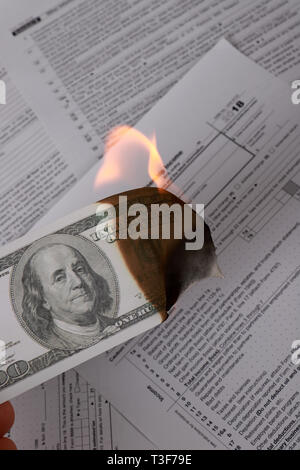 1065 tax form and a burning hundred dollar bill on a Table. US Return for parentship income Stock Photo