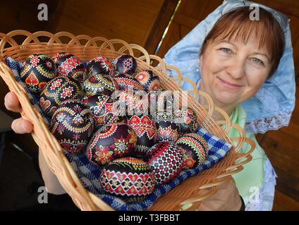 06 April 2019, Brandenburg, Lübbenau: Marita Muckwar, artist, wears a Sorbian-Wendish festive costume and shows chicken eggs decorated with the wax batik technique. Photo: Patrick Pleul/dpa-Zentralbild/ZB Stock Photo