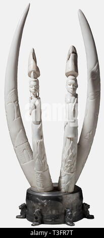 Four carved elephant's tusks, Africa, circa 1960 Two pairs of figuratively and florally carved tusks of different sizes, mounted on a round tin base. Total height 89 cm, length of the tusks 64 and 80 cm. Total weight without base circa 20 kg. CITES certifications available. historic, historical, 1950s, 1960s, 20th century, 20th century, Africa, African, weapon, arms, weapons, arms, fighting device, object, objects, clipping, cut out, cut-out, cut-outs, militaria, Additional-Rights-Clearance-Info-Not-Available Stock Photo