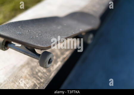 Professional skateboard laying on concrete ledge at skate park. Practice freestyle, urban extreme sport activity for youth, staying out of trouble Stock Photo