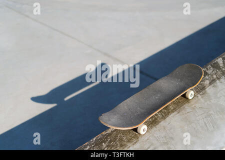Professional skateboard laying on concrete ledge at skate park. Practice freestyle, urban extreme sport activity for youth, staying out of trouble Stock Photo