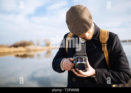 Photographer with vintage photo camera. Bearded man using retro camera outdoor Stock Photo