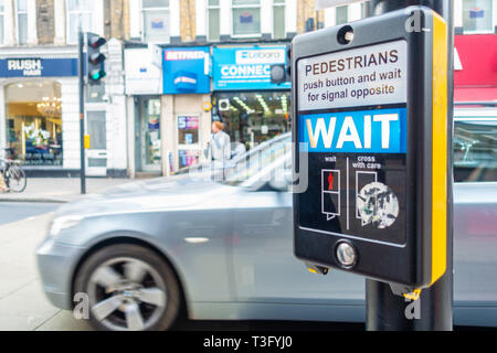 Close up vie of a sign telling pedestrians to wait at a pedestrian crossing in Earl's Court, London Stock Photo