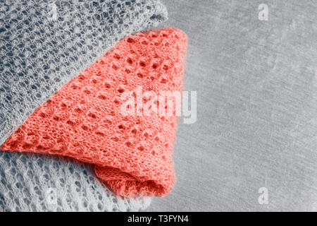 Pile of stylish knitted pastel colored sweaters and one in color of the year 2019. Top view. Copy space. Stock Photo