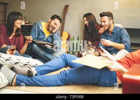 Happy young friends having fun at home listening vintage vinyl disc music in living room - Group of people enjoying their time in apartment Stock Photo