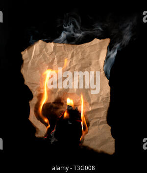 burning piece of crumpled paper on black background Stock Photo