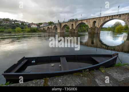 Wooden boat next to the medieval stone bridge over the Lima river in Ponte da Barca, Minho, Portugal, Europe Stock Photo