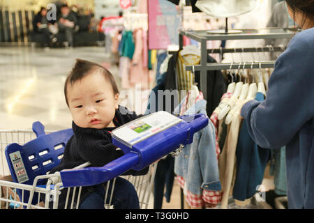Asian mother and her baby boy shopping in clothing store Stock Photo