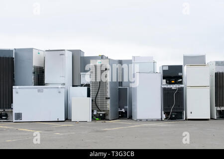 Old fridges freezers refrigerant gas at refuse dump skip recycle stacked pile plant help environment reduce pollution white silver Stock Photo