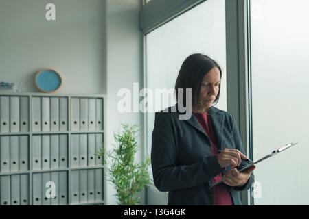 Concerned businesswoman reading business report papers in office, financial data analysis and strategic operations planning concept Stock Photo