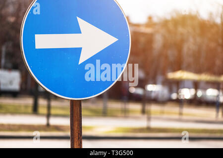 Proceed in direction arrow traffic sign on the street with defocussed background Stock Photo