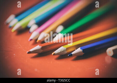Group of pencils lined up in a red table used by a kid to draw with an old look Stock Photo