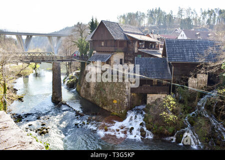 Rastoke, Croatia - March 7 2019: Bridge over river leading to old town. Interesting small waterfalls around old town. Stock Photo