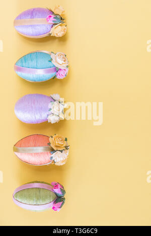 Row of vintage style multi-colored Easter eggs on sold yellow background Stock Photo