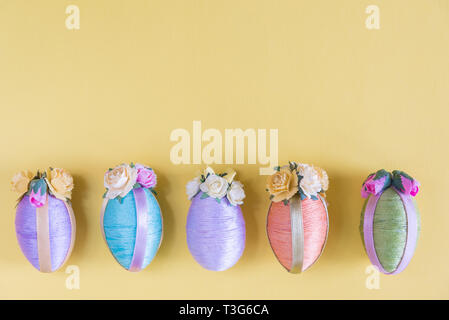 Multi-color vintage style Easter eggs in row on solid yellow background Stock Photo