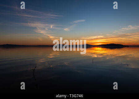 Symmetrcal, beautiful view of Trasimeno lake (Umbria, Italy) at sunset, with orange and blue tones in the sky Stock Photo