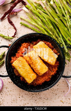 high angle view of a frying pan with bacalao a la vizcaina, a typical spanish recipe of codfish, with tomato, garlic, onion and red pepper, on a rusti Stock Photo