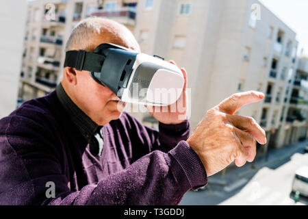 closeup of an old caucasian man using a virtual reality headset outdoors Stock Photo