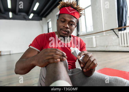 Short-haired good-looking man dealing with injured knee Stock Photo