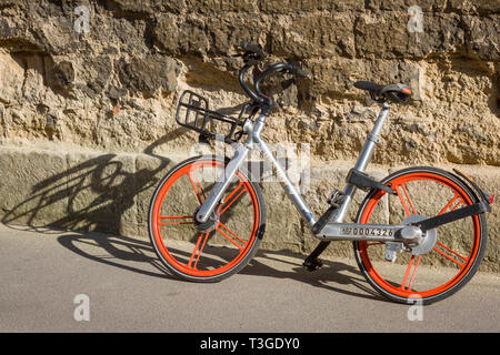 a Mobike hire bike against a crumbling stone wall in Oxford Stock Photo