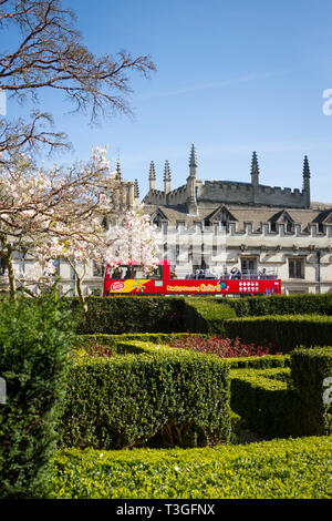 An open top double-decker tour bus passing Magdalen College, Oxford Stock Photo