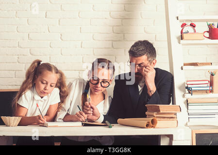 Back to school and home schooling. School time of girl sisters with father. Education and knowledge day. Father helps children to study at home Stock Photo