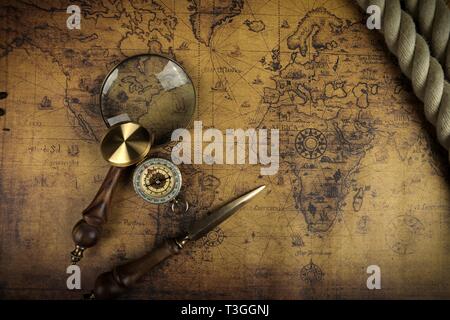 Vintage Compass and magnifying glass lies on an ancient world map - adventure stories background Stock Photo