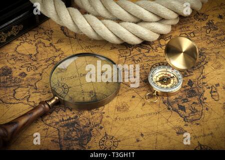 Vintage Compass and magnifying glass lies on an ancient world map - adventure stories background Stock Photo