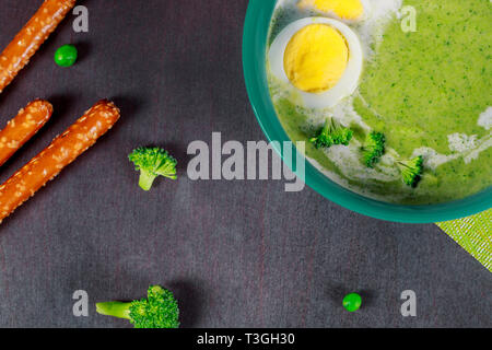 Light summer green broccoli and eggs cream soup in bowl with wooden background. Top view Stock Photo