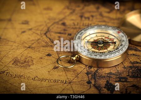 Vintage Compass lies on an ancient world map - adventure stories background Stock Photo